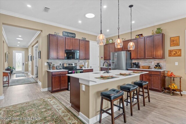 2889 Millennium Cir, Melbourne, FL 32940 - kitchen with appliances with stainless steel finishes, a sink, light wood finished floors, light countertops, and a kitchen breakfast bar