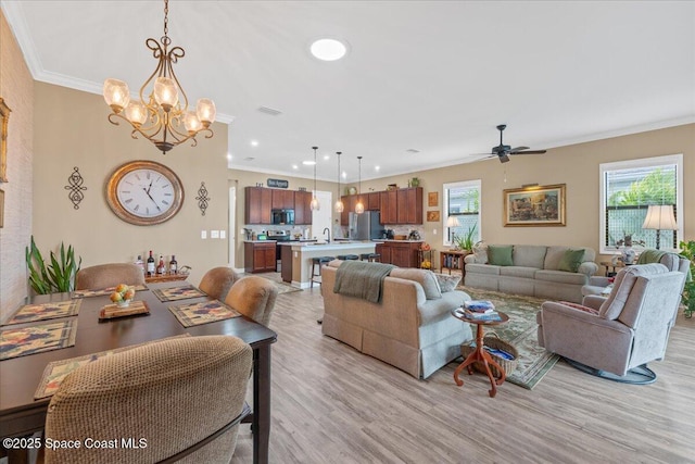 2889 Millennium Cir, Melbourne, FL 32940 - living room featuring a chandelier, crown molding, light wood finished floors, ceiling fan, and recessed lighting