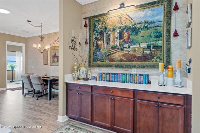 2889 Millennium Cir, Melbourne, FL 32940 - bar area featuring a chandelier, light wood-style flooring, ornamental molding, baseboards, and decorative light fixtures