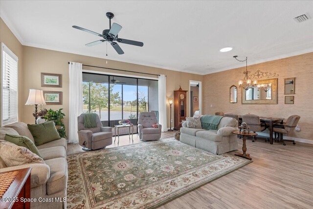 2889 Millennium Cir, Melbourne, FL 32940 - living room featuring healthy amount of natural light, a chandelier, wood finished floors, baseboards, and ornamental molding