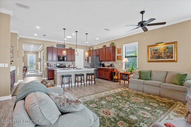 2889 Millennium Cir, Melbourne, FL 32940 - living room with a ceiling fan, light wood-type flooring, recessed lighting, crown molding, and baseboards