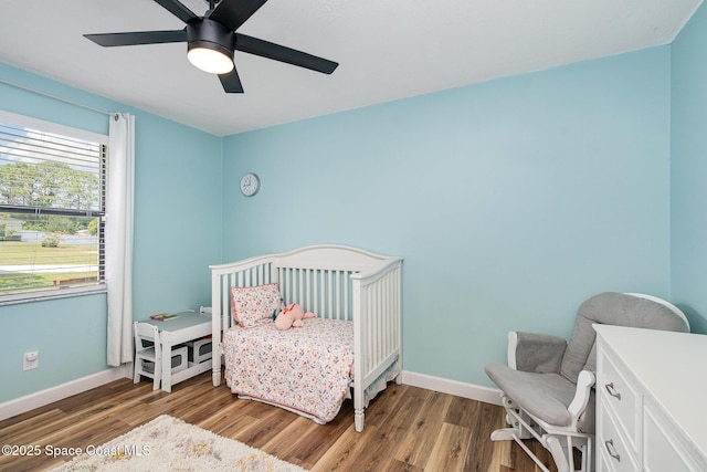 1035 Blau Ct NW, Palm Bay, FL 32907 - bedroom with wood finished floors, baseboards, ceiling fan, and a nursery area