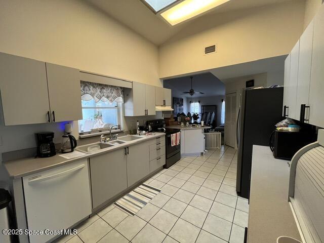 130 Nemo Cir NE, Palm Bay, FL 32907 - kitchen with black appliances, high vaulted ceiling, under cabinet range hood, light tile patterned floors, and a sink
