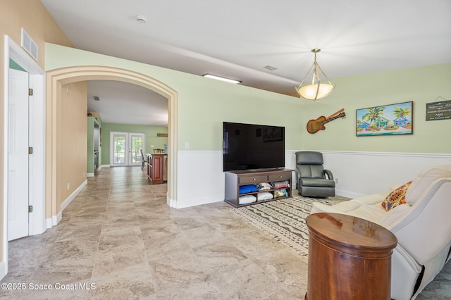 1317 Mohegan Ter SE, Palm Bay, FL 32909 - living room with arched walkways, french doors, baseboards, and wainscoting