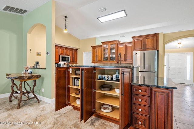 1317 Mohegan Ter SE, Palm Bay, FL 32909 - kitchen featuring stainless steel appliances, arched walkways, glass insert cabinets, brown cabinetry, and vaulted ceiling
