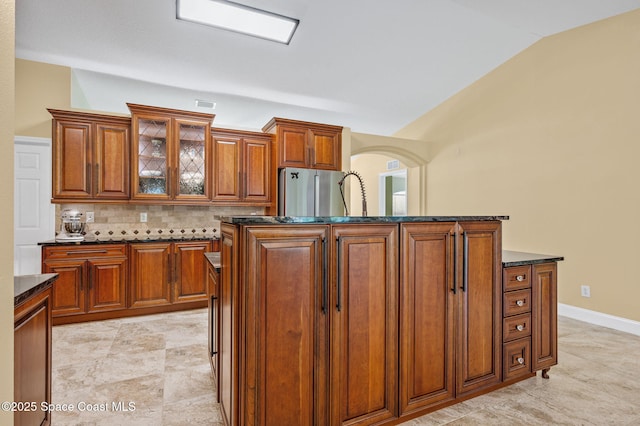 1317 Mohegan Ter SE, Palm Bay, FL 32909 - kitchen featuring lofted ceiling, freestanding refrigerator, tasteful backsplash, brown cabinets, and glass insert cabinets