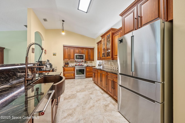 1317 Mohegan Ter SE, Palm Bay, FL 32909 - kitchen with appliances with stainless steel finishes, lofted ceiling, brown cabinetry, dark stone countertops, and tasteful backsplash