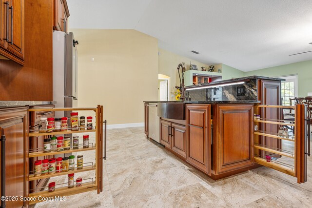 1317 Mohegan Ter SE, Palm Bay, FL 32909 - kitchen featuring vaulted ceiling, brown cabinets, dark stone countertops, a sink, and a kitchen island