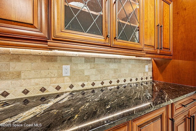 1317 Mohegan Ter SE, Palm Bay, FL 32909 - kitchen featuring brown cabinets, glass insert cabinets, dark stone counters, and backsplash