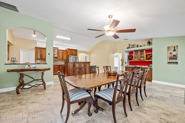 1317 Mohegan Ter SE, Palm Bay, FL 32909 - dining area with arched walkways, ceiling fan, baseboards, lofted ceiling, and a textured ceiling