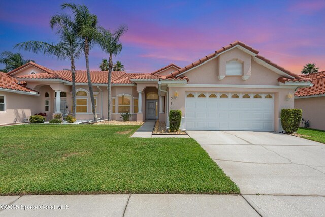 570 Shell Cove Dr, Melbourne, FL 32940 - mediterranean / spanish house featuring concrete driveway, a lawn, a garage, stucco siding, and a tiled roof