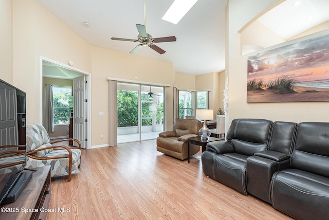 570 Shell Cove Dr, Melbourne, FL 32940 - living room with ceiling fan, light wood-style flooring, high vaulted ceiling, baseboards, and a skylight