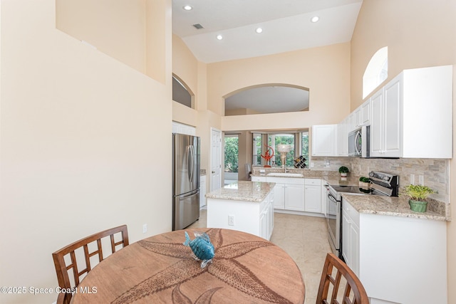 570 Shell Cove Dr, Melbourne, FL 32940 - kitchen with stainless steel appliances, a high ceiling, white cabinets, recessed lighting, and backsplash