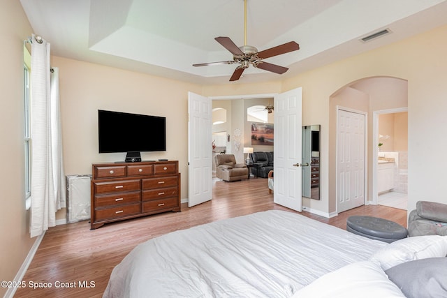570 Shell Cove Dr, Melbourne, FL 32940 - bedroom with arched walkways, light wood finished floors, baseboards, and ensuite bath