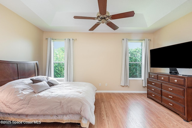 570 Shell Cove Dr, Melbourne, FL 32940 - bedroom featuring a raised ceiling, light wood-type flooring, baseboards, and ceiling fan