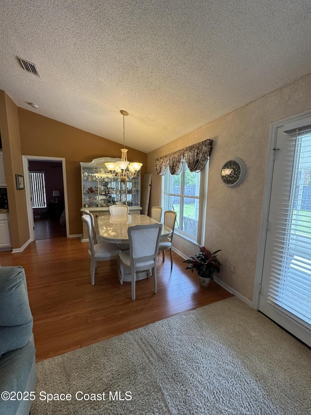 157 Lehigh Ave SE, Palm Bay, FL 32909 - dining space with a textured ceiling, a chandelier, vaulted ceiling, wood finished floors, and baseboards