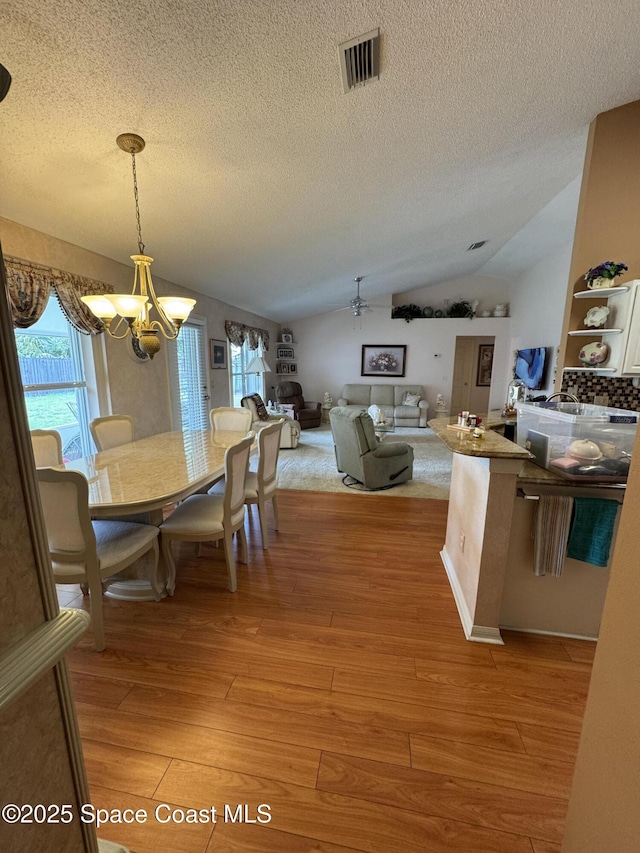 157 Lehigh Ave SE, Palm Bay, FL 32909 - dining space featuring a chandelier, a textured ceiling, lofted ceiling, light wood-type flooring, and a ceiling fan