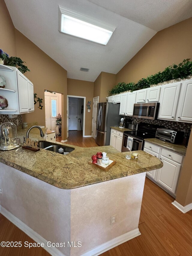157 Lehigh Ave SE, Palm Bay, FL 32909 - kitchen featuring appliances with stainless steel finishes, lofted ceiling, a sink, open shelves, and white cabinets