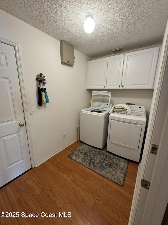 157 Lehigh Ave SE, Palm Bay, FL 32909 - washroom featuring cabinet space, a textured ceiling, washer and dryer, and wood finished floors
