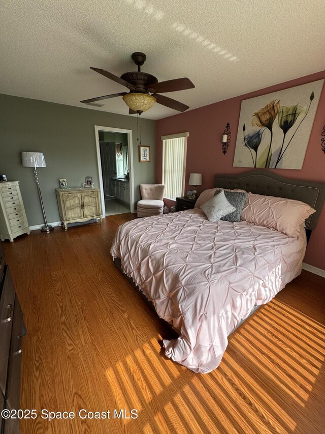 157 Lehigh Ave SE, Palm Bay, FL 32909 - bedroom featuring wood finished floors, a textured ceiling, baseboards, ceiling fan, and ensuite bathroom