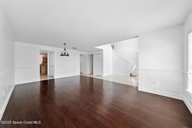 1500 La Maderia Dr SW, Palm Bay, FL 32908 - unfurnished living room with a chandelier, wood finished floors, a textured ceiling, stairway, and baseboards