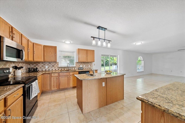 1500 La Maderia Dr SW, Palm Bay, FL 32908 - kitchen with stainless steel microwave, black range with electric stovetop, decorative backsplash, a center island with sink, and light stone countertops