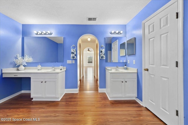 1500 La Maderia Dr SW, Palm Bay, FL 32908 - bathroom featuring wood finished floors, two vanities, baseboards, and a textured ceiling