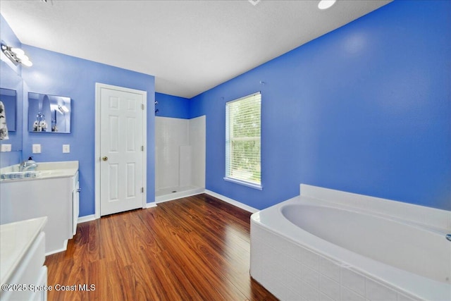 1500 La Maderia Dr SW, Palm Bay, FL 32908 - bathroom with vanity, a bath, a walk in shower, wood finished floors, and baseboards