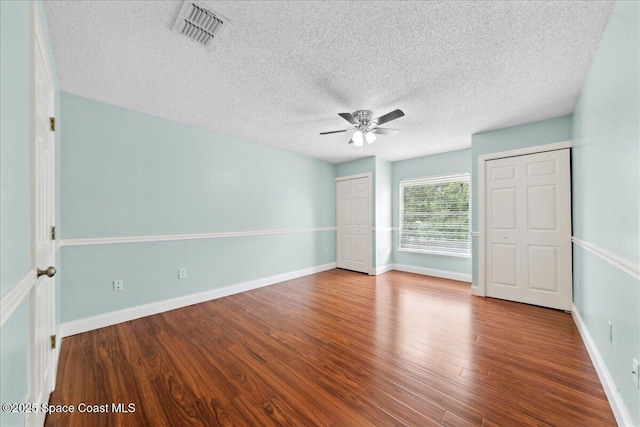1500 La Maderia Dr SW, Palm Bay, FL 32908 - unfurnished bedroom with wood finished floors, a textured ceiling, multiple closets, a ceiling fan, and baseboards