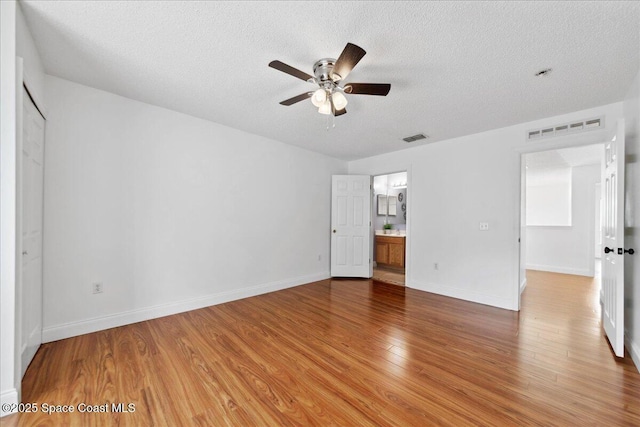 1500 La Maderia Dr SW, Palm Bay, FL 32908 - unfurnished bedroom featuring a textured ceiling, light wood-type flooring, baseboards, ensuite bathroom, and a ceiling fan