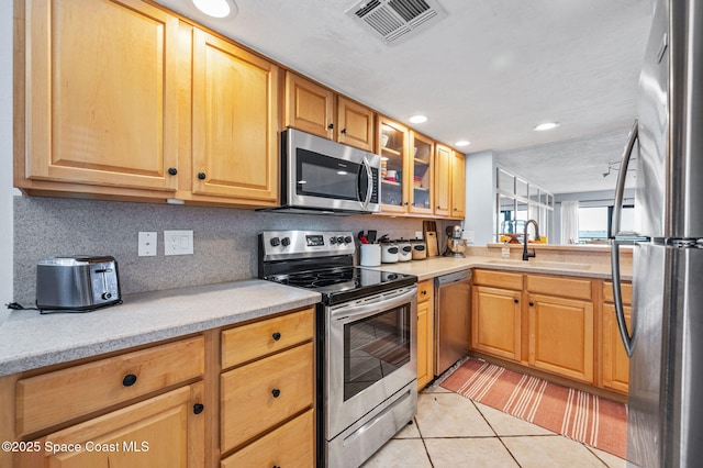 3901 Dixie Hwy NE Unit 301, Palm Bay, FL 32905 - kitchen with stainless steel appliances, a sink, light countertops, glass insert cabinets, and light tile patterned floors