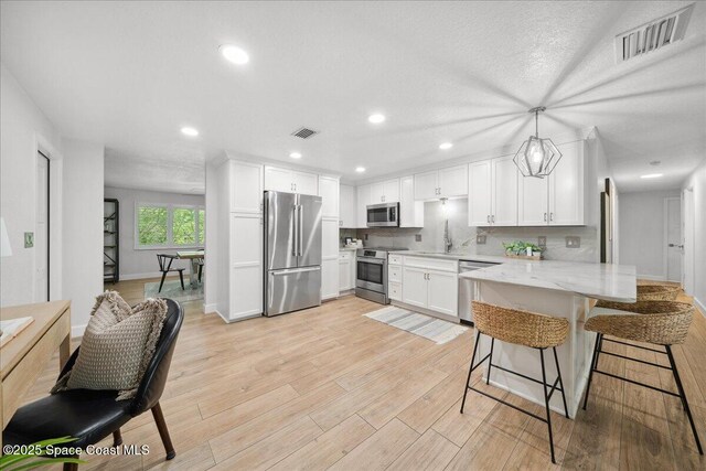 629 Verbenia Dr, Satellite Beach, FL 32937 - kitchen featuring appliances with stainless steel finishes, a peninsula, white cabinets, light stone countertops, and recessed lighting