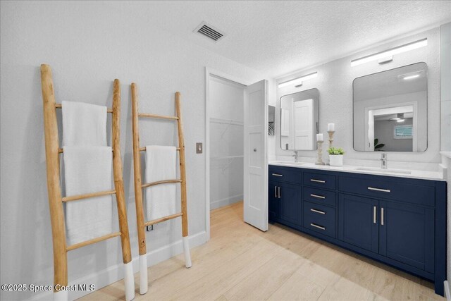 629 Verbenia Dr, Satellite Beach, FL 32937 - full bath featuring double vanity, wood finished floors, a textured ceiling, and a walk in closet