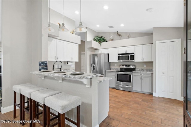 1911 Crane Creek Blvd, Melbourne, FL 32940 - kitchen featuring stainless steel appliances, high vaulted ceiling, a kitchen bar, a peninsula, and light wood finished floors