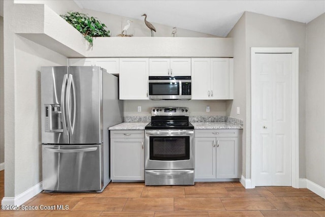 1911 Crane Creek Blvd, Melbourne, FL 32940 - kitchen featuring stainless steel appliances, vaulted ceiling, wood tiled floors, baseboards, and light stone counters
