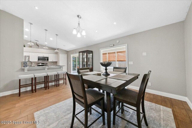 1911 Crane Creek Blvd, Melbourne, FL 32940 - dining room featuring light wood finished floors, vaulted ceiling, a chandelier, baseboards, and recessed lighting