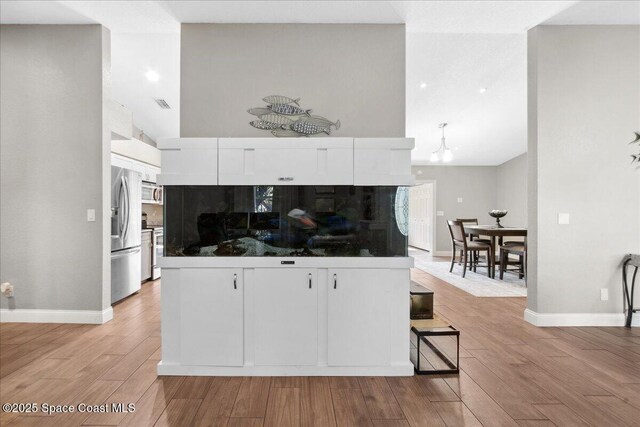 1911 Crane Creek Blvd, Melbourne, FL 32940 - kitchen featuring stainless steel refrigerator with ice dispenser, white cabinets, light wood-type flooring, and lofted ceiling