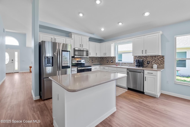 1685 Timacuan Dr, Melbourne, FL 32940 - kitchen with appliances with stainless steel finishes, backsplash, vaulted ceiling, light wood-type flooring, and white cabinetry