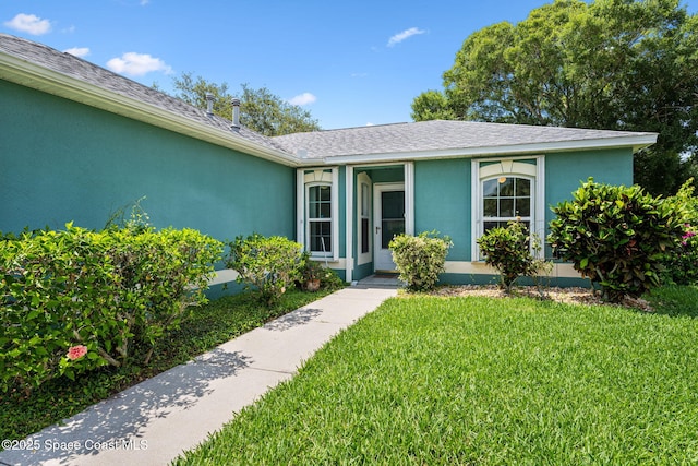 2719 Alicia Ln, Melbourne, FL 32935 - view of front facade featuring stucco siding, a front yard, and roof with shingles