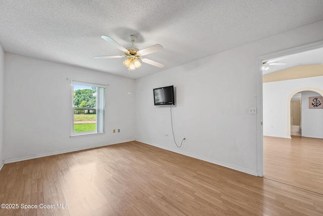 2719 Alicia Ln, Melbourne, FL 32935 - spare room featuring a ceiling fan, arched walkways, light wood-type flooring, a textured ceiling, and baseboards