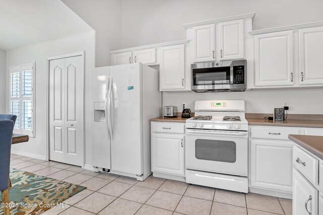 1545 Boca Rio Dr, Melbourne, FL 32940 - kitchen featuring white appliances, light tile patterned floors, and white cabinets
