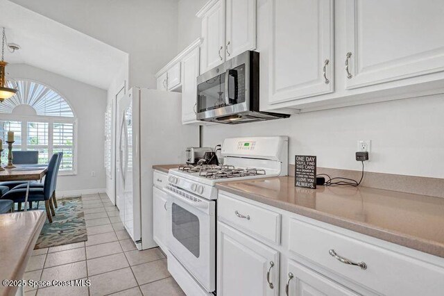 1545 Boca Rio Dr, Melbourne, FL 32940 - kitchen featuring white appliances, white cabinetry, light tile patterned flooring, lofted ceiling, and light countertops