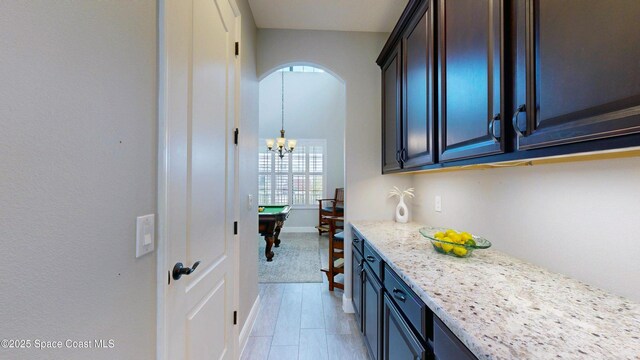 8051 Strom Park Dr, Melbourne, FL 32940 - kitchen featuring arched walkways, light stone counters, a chandelier, and baseboards