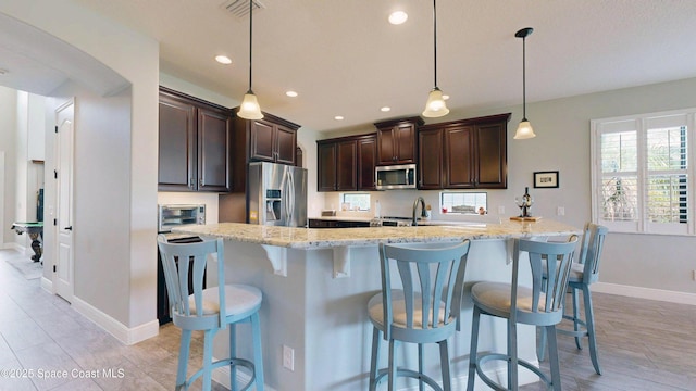 8051 Strom Park Dr, Melbourne, FL 32940 - kitchen with appliances with stainless steel finishes, dark brown cabinets, baseboards, a breakfast bar area, and recessed lighting