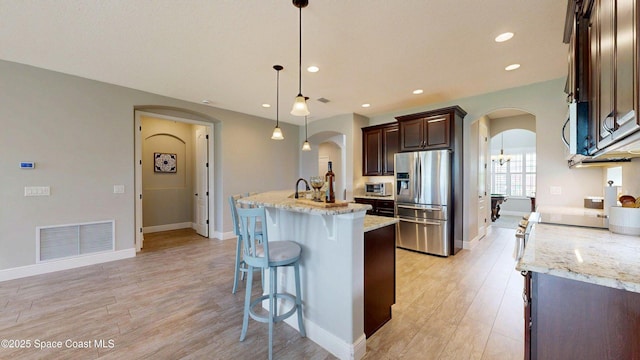 8051 Strom Park Dr, Melbourne, FL 32940 - kitchen with appliances with stainless steel finishes, arched walkways, dark brown cabinets, light wood-style flooring, and light stone counters