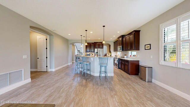 8051 Strom Park Dr, Melbourne, FL 32940 - kitchen with appliances with stainless steel finishes, arched walkways, a breakfast bar area, light countertops, and light wood-type flooring