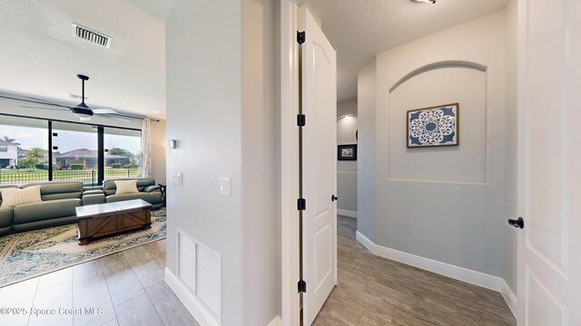 8051 Strom Park Dr, Melbourne, FL 32940 - hallway featuring baseboards, a textured ceiling, and light wood-style floors