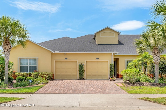 5928 Van Ness Dr, Melbourne, FL 32940 - view of property with decorative driveway, an attached garage, a shingled roof, and stucco siding