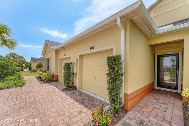 5928 Van Ness Dr, Melbourne, FL 32940 - view of side of property featuring a garage, stucco siding, and decorative driveway