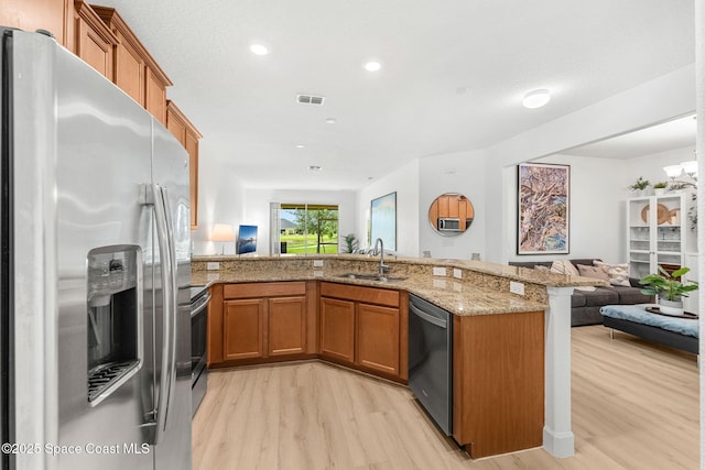 5928 Van Ness Dr, Melbourne, FL 32940 - kitchen featuring appliances with stainless steel finishes, open floor plan, a sink, brown cabinetry, and light wood-style flooring